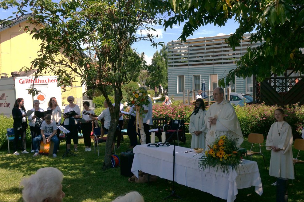 Der Pfarrer beim Altar, im Hintergrund zwei MinistrantInnen und die Musikgruppe.