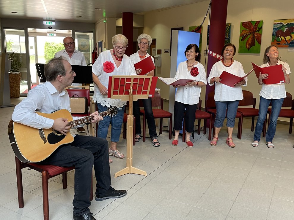 Ein Herr spielt Gitarre, Frauen singen.