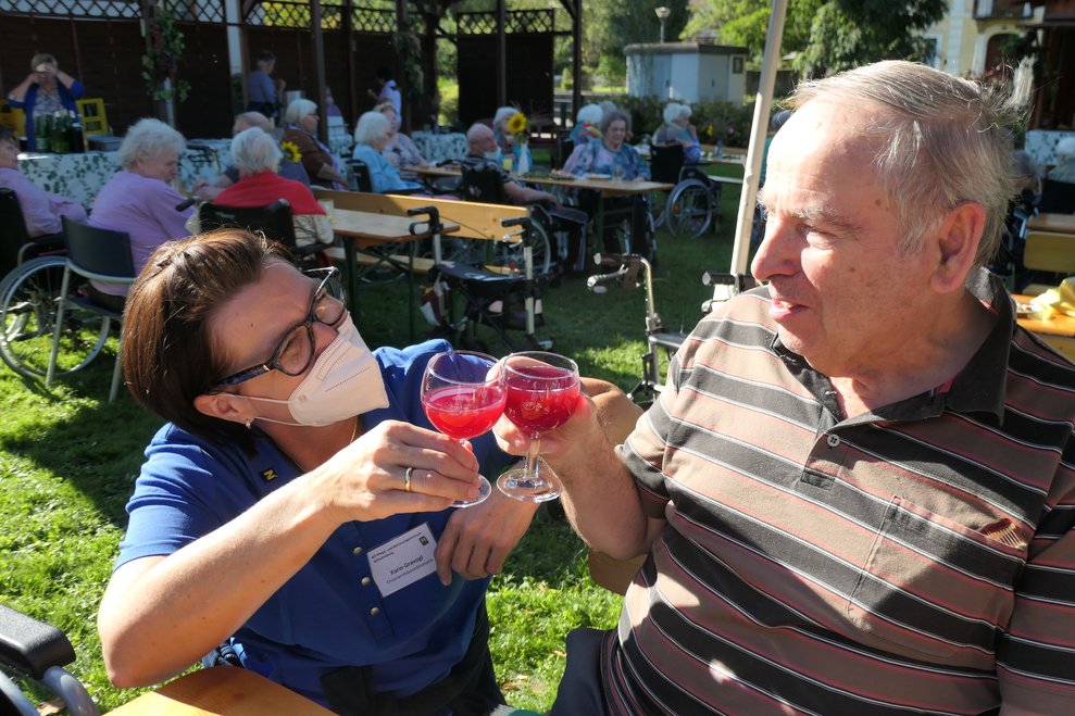 Zwei Personen stoßen mit einem Glas roten Sturm an.