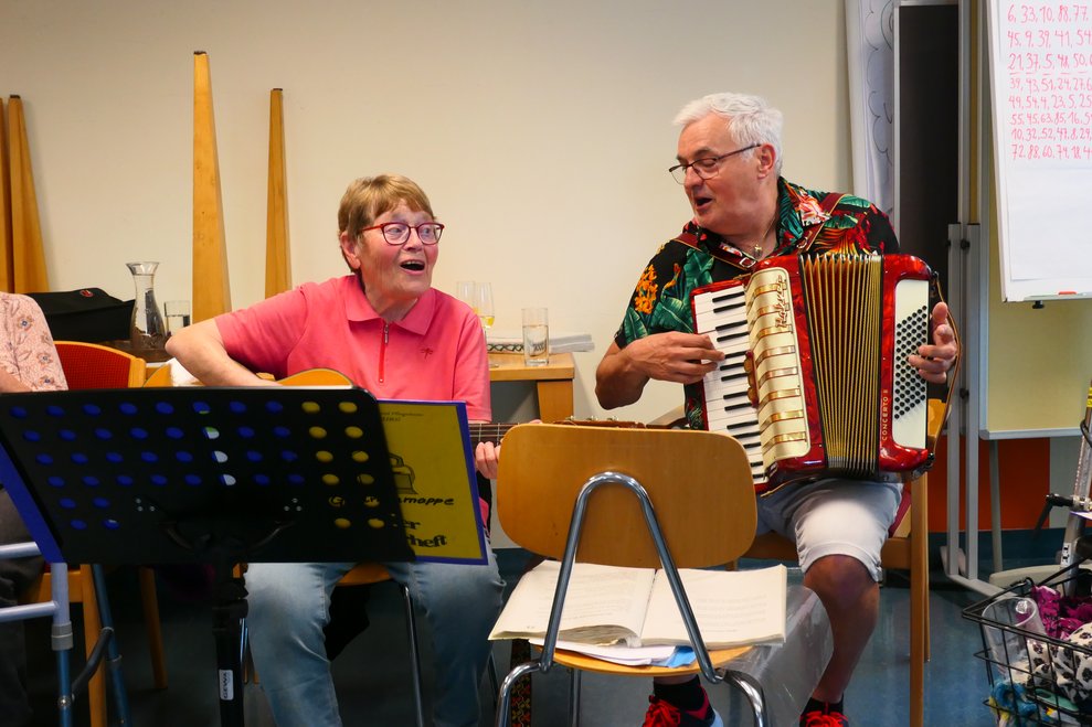 Herta Moser an der Gitarre, ein Herr spielt Zieharmonika.