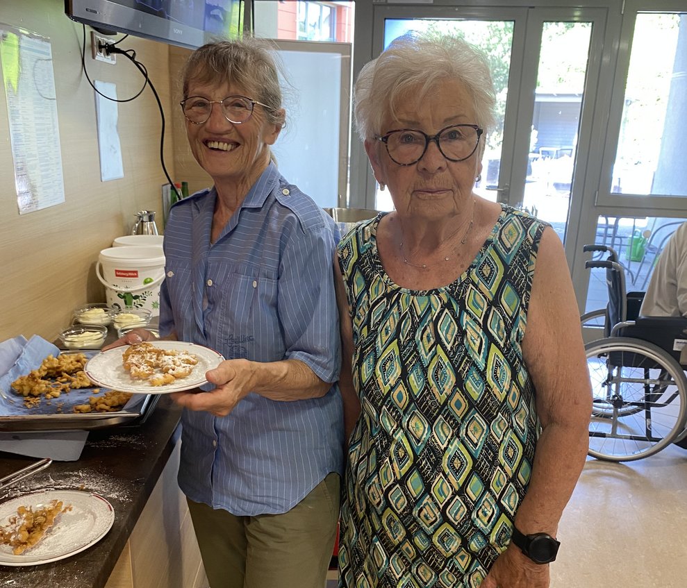 Ehrenamtliche Miarbeiterinnen Marianne und Lucja, servieren den frisch angezuckerten Holler.