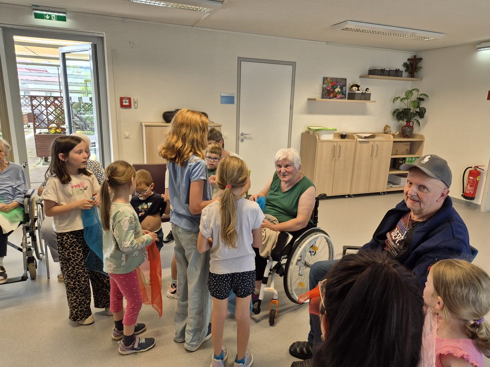Alle Kinder stehen bei einer älteren Dame.