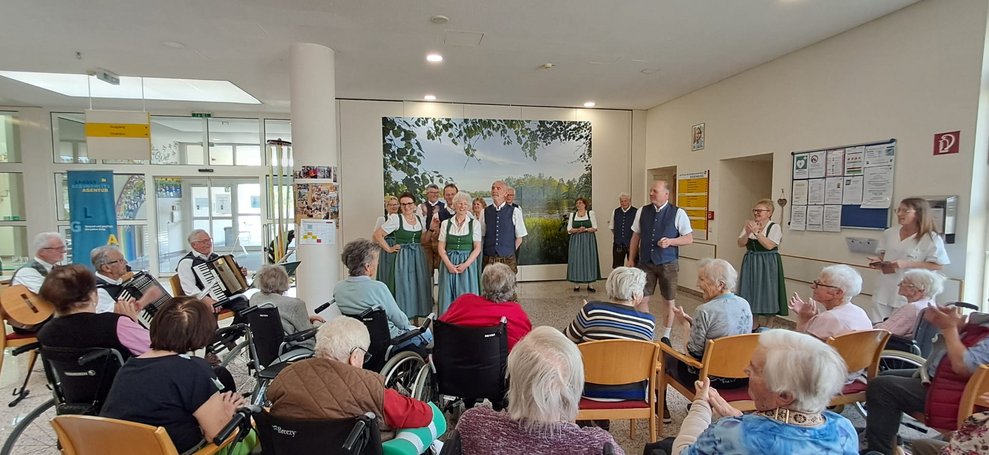 MitgliederInnen der Volkstanzgruppe Rosenburg/Mold zeigen Tänze. Viele sitzende BewohnerInnen.