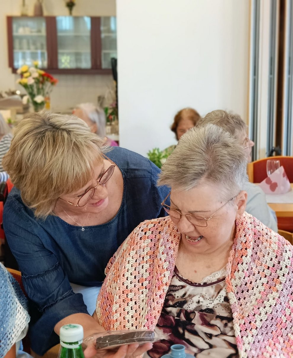 Pflegedirektorin gibt Bewohnerin Schokomuttertagsherz.