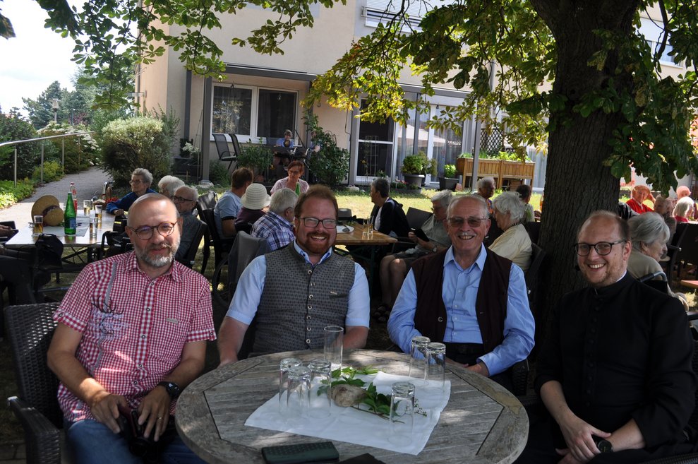 einige Menschen bei Tisch im Garten