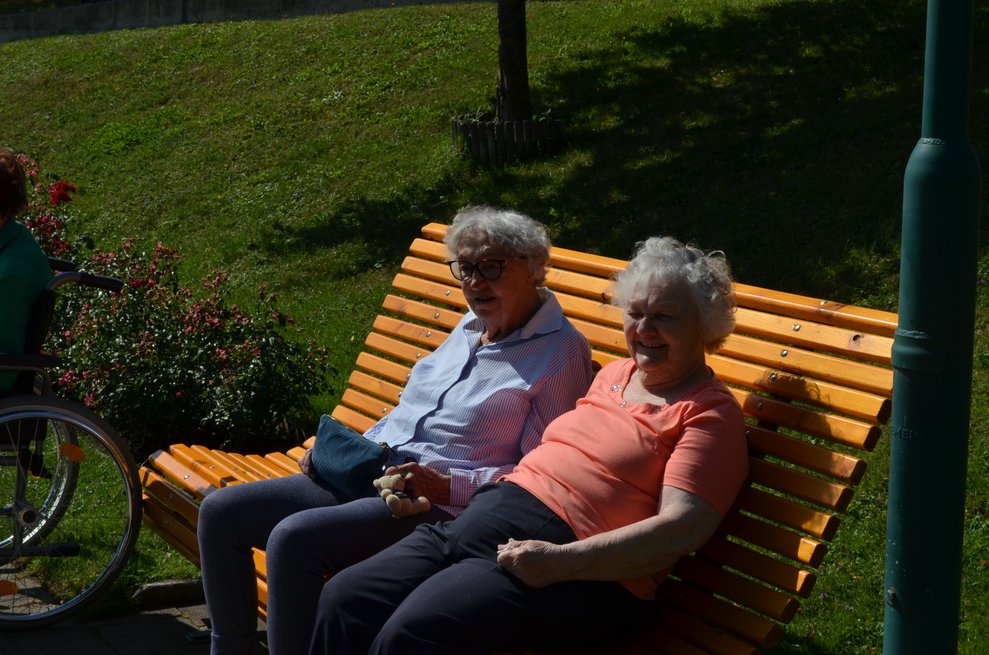 Zwei Damen sitzen entspannt auf der Bank und genießen die Aussicht. 