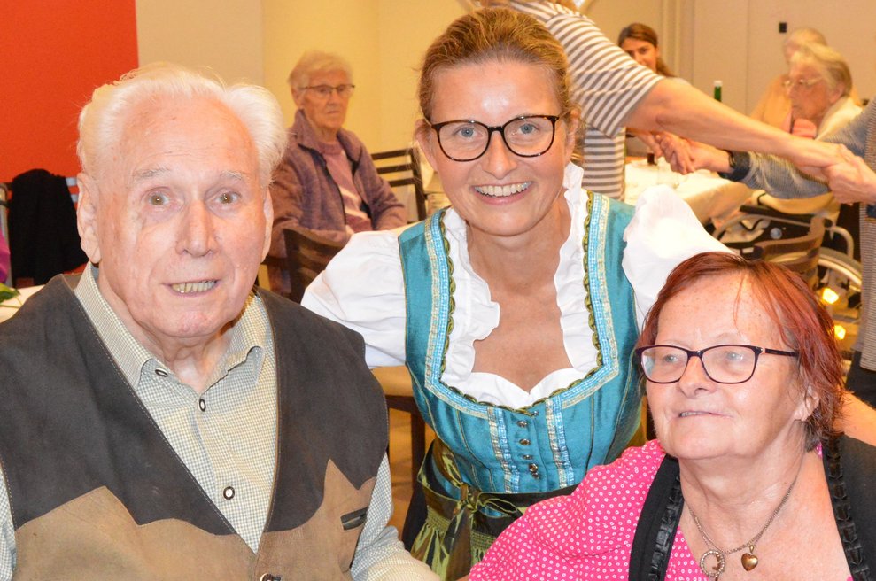 Eine Betreuerin in Tracht mit zwei BewohnerInnen.