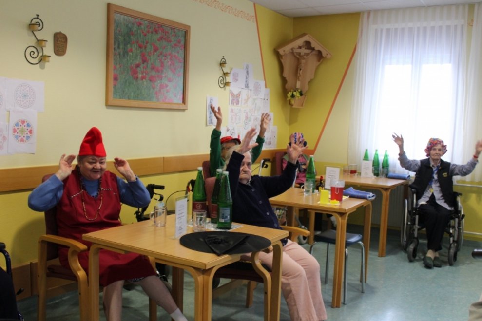 BewohnerInnen sitzen bei Tischen.