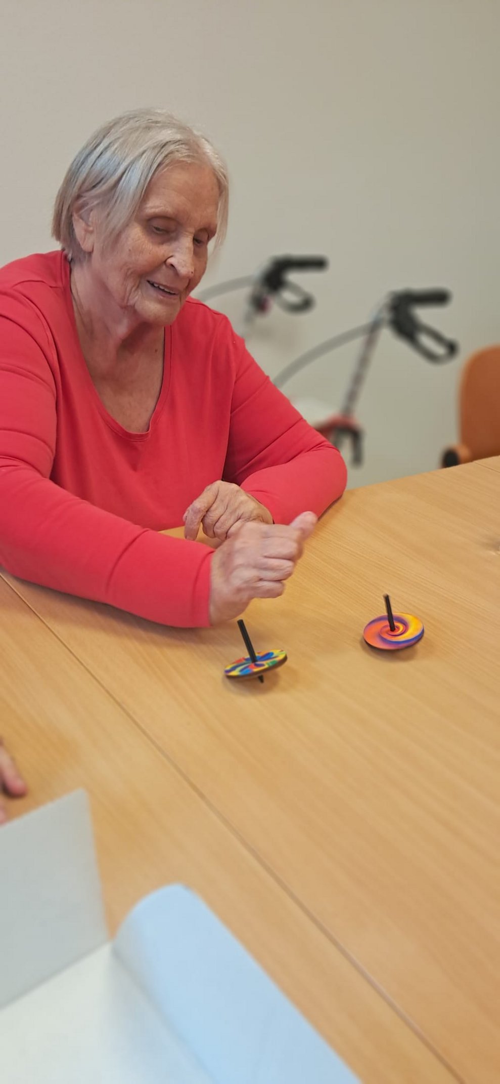 Bewohnerin spielt mit Kreiseln auf Tisch.