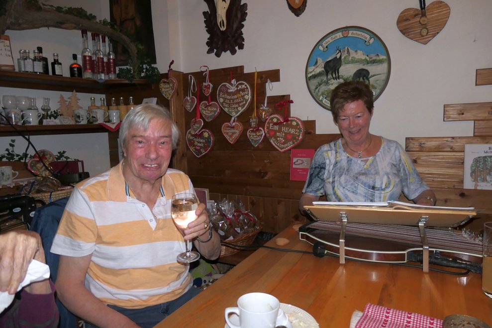 Eine Dame an der Zither und ein Herr mit einem Glas