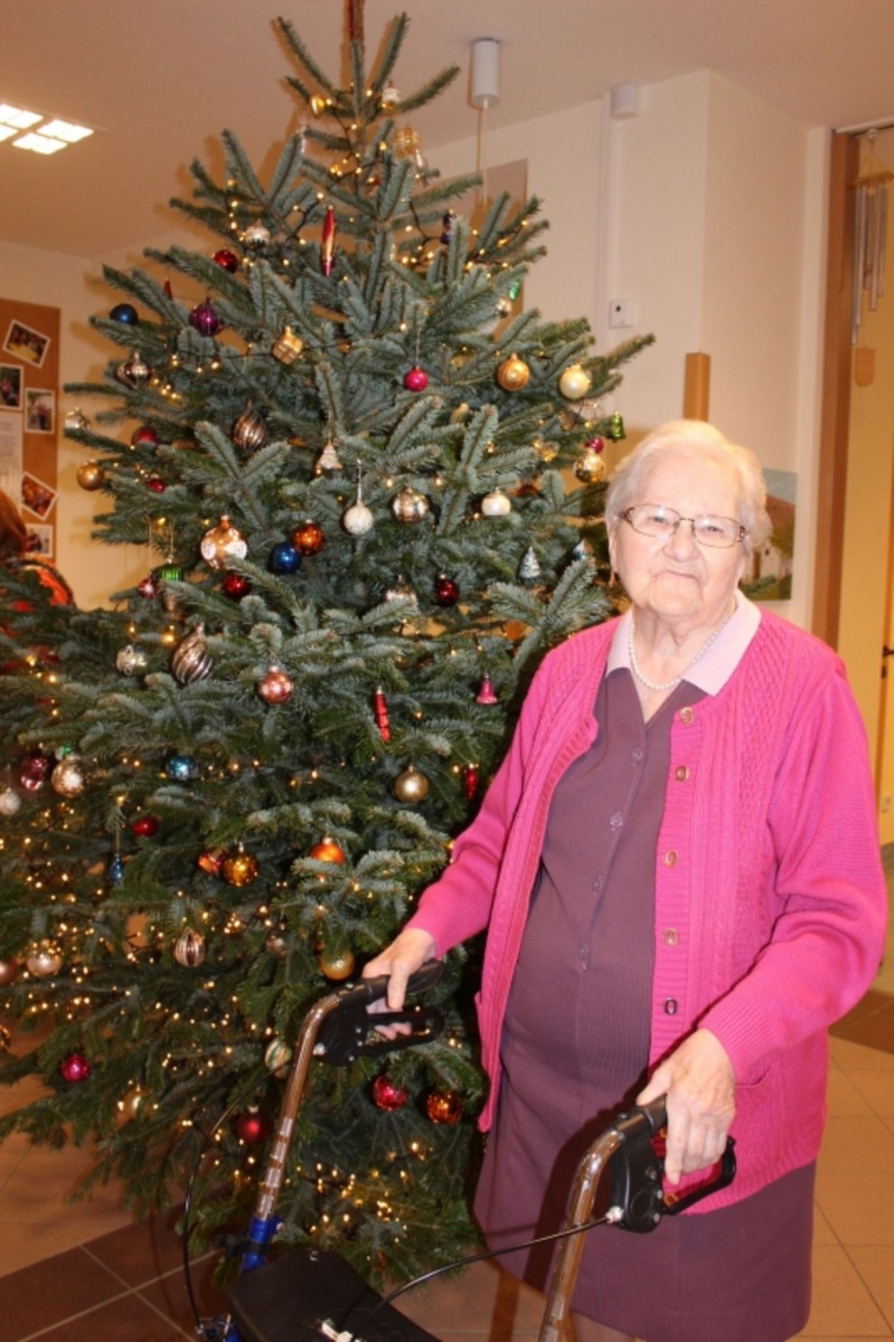 Eine Bewohnerin steht beim Christbaum.