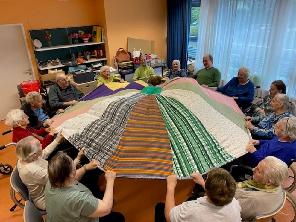 Bewohnerinnen und Bewohner heben die Decke in die Höhe