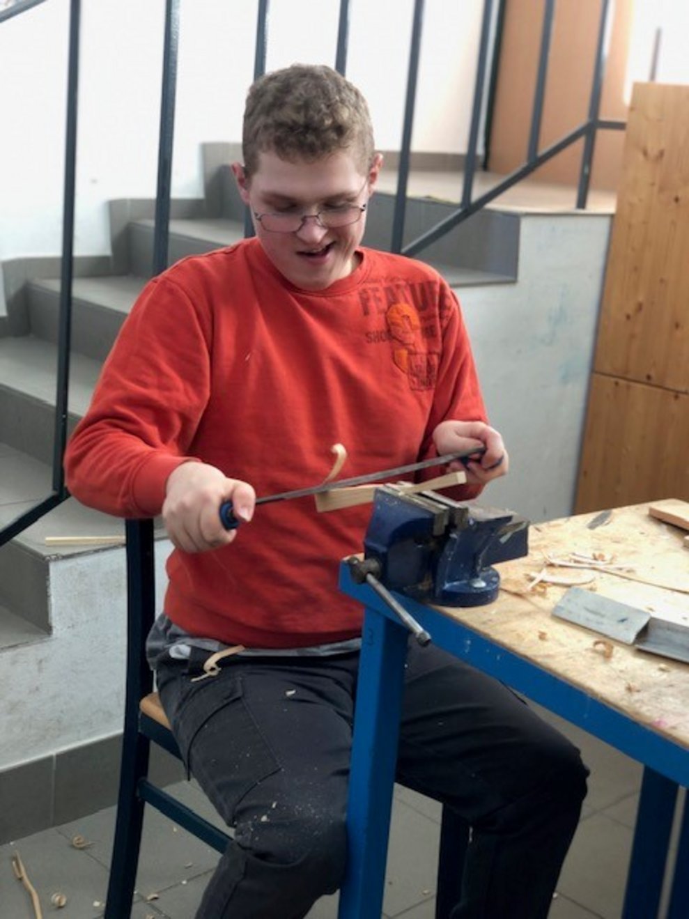 Ein junger Mann macht aus einem Holzstück Holzlocken.