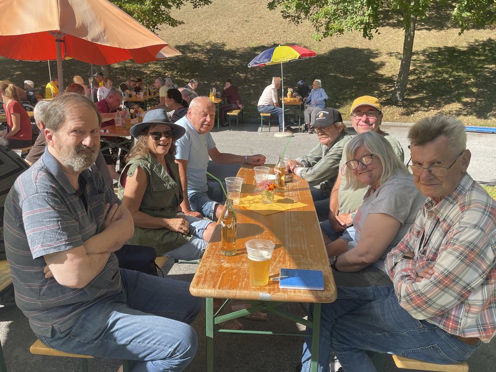 Männer und Frauen sitzen um einen Tisch.