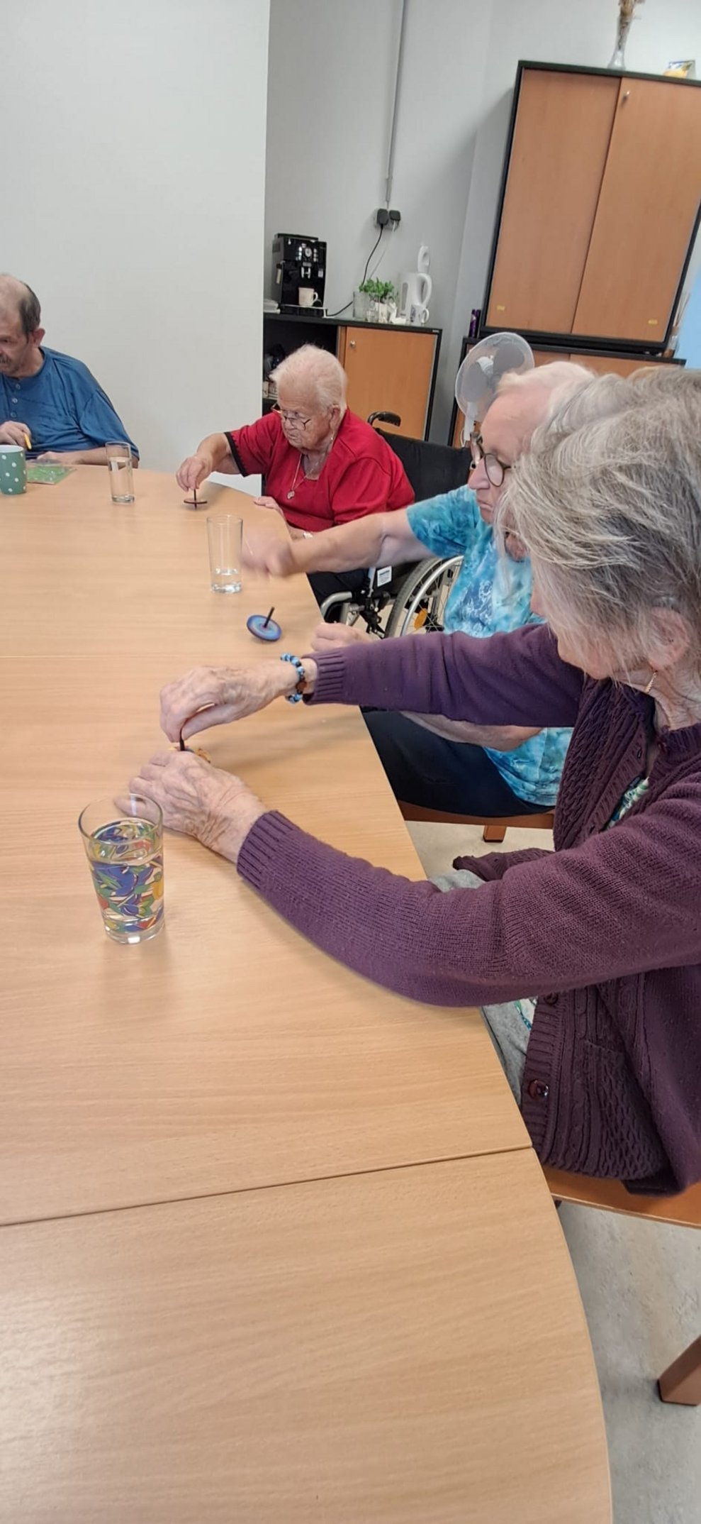 Bewohnerinnen spielen mit Kreiseln auf Tisch.
