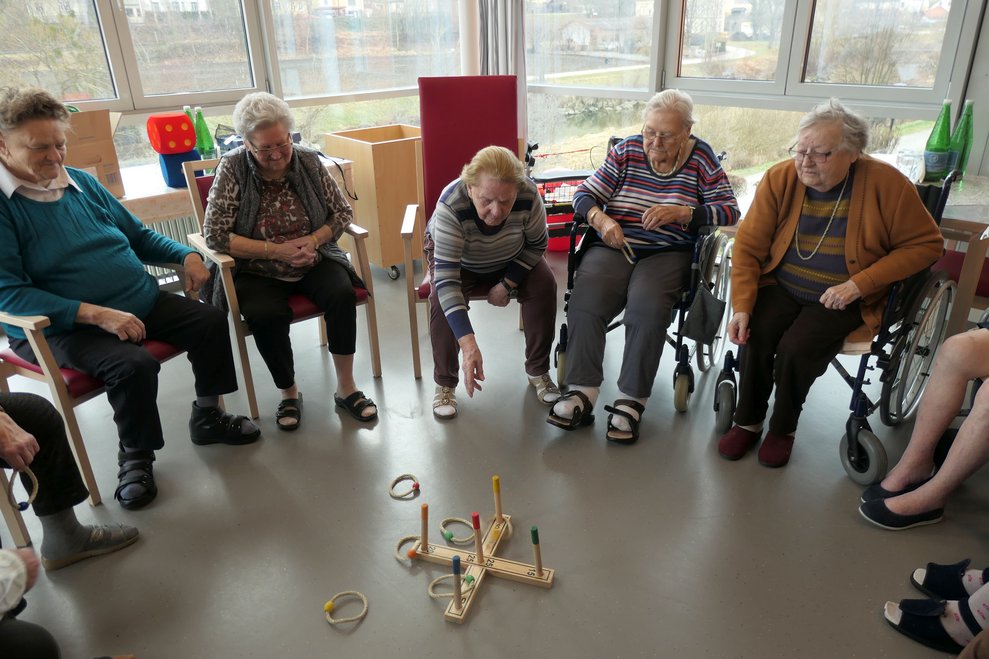 Die Bewohner: innen spielen das Ringwurfspiel