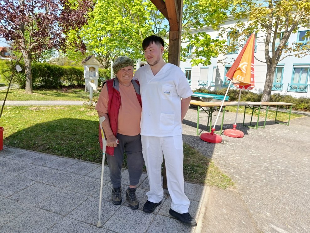Bewohnerin und Mitarbeiter lächeln.