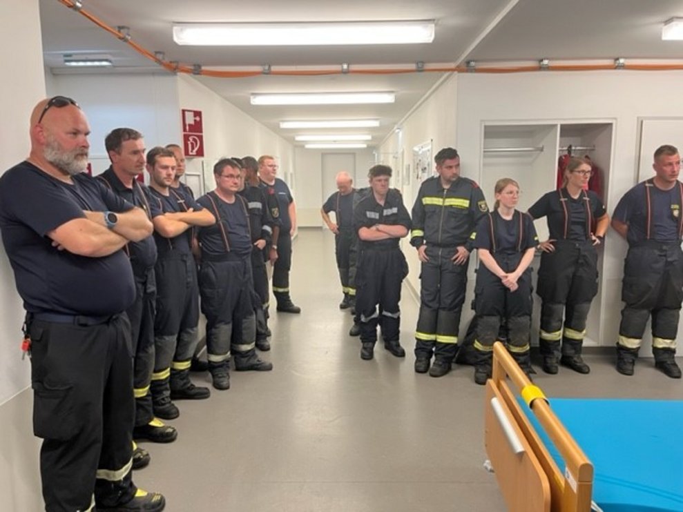 Einige Feuerwehrleute stehen um ein Bett.