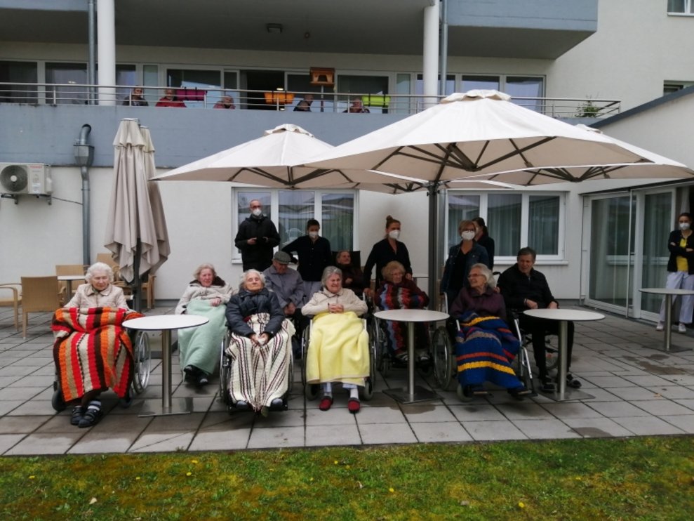 BewohnerInnen sitzen auf der Terrasse.
