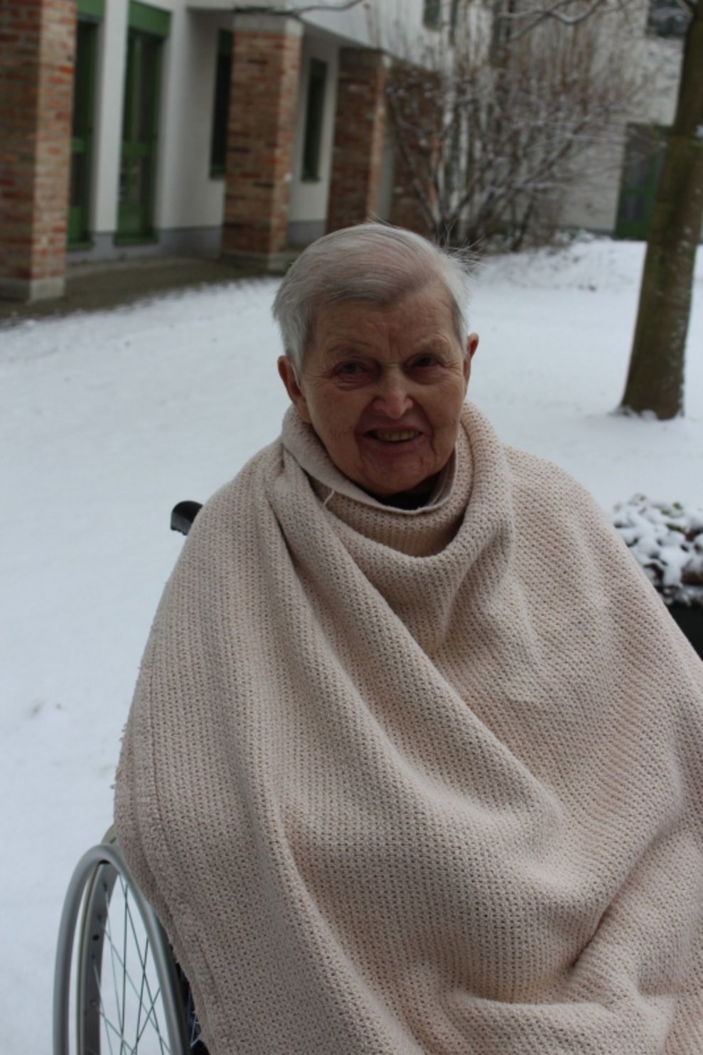 Eine Bewohnerin ist draußen beim Schnee.