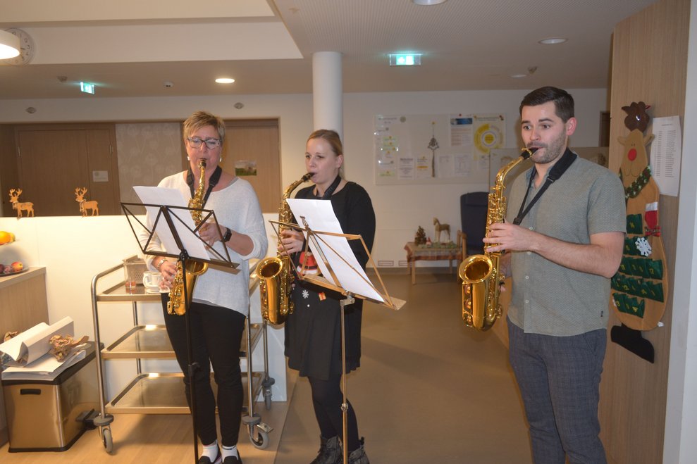 Drei Mitarbeiter*innen mit Saxophon. 