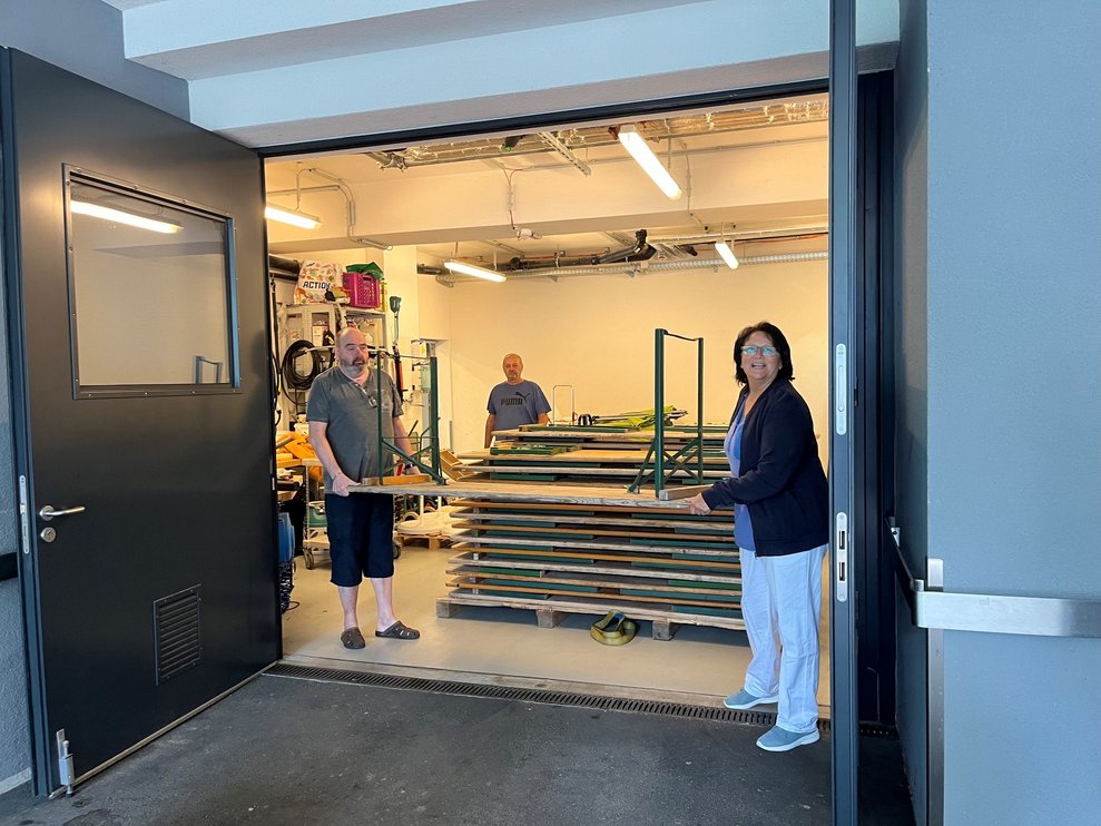 Bewohner und Mitarbeiterin tragen eine Heurigenbank aus der Garage.