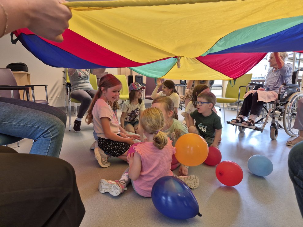 Einige Kinder sitzen unter dem "Fallschirm"