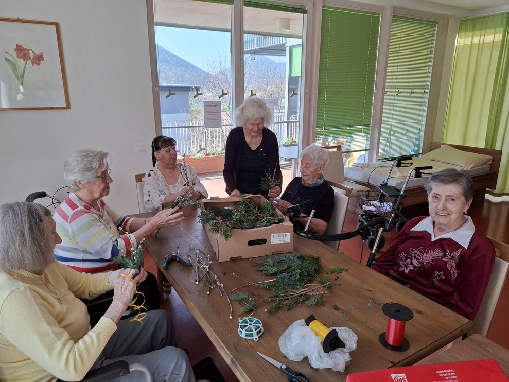 Eine gesellige Damenrunde hat sich um "Palmbesen-Binden" eingefunden.