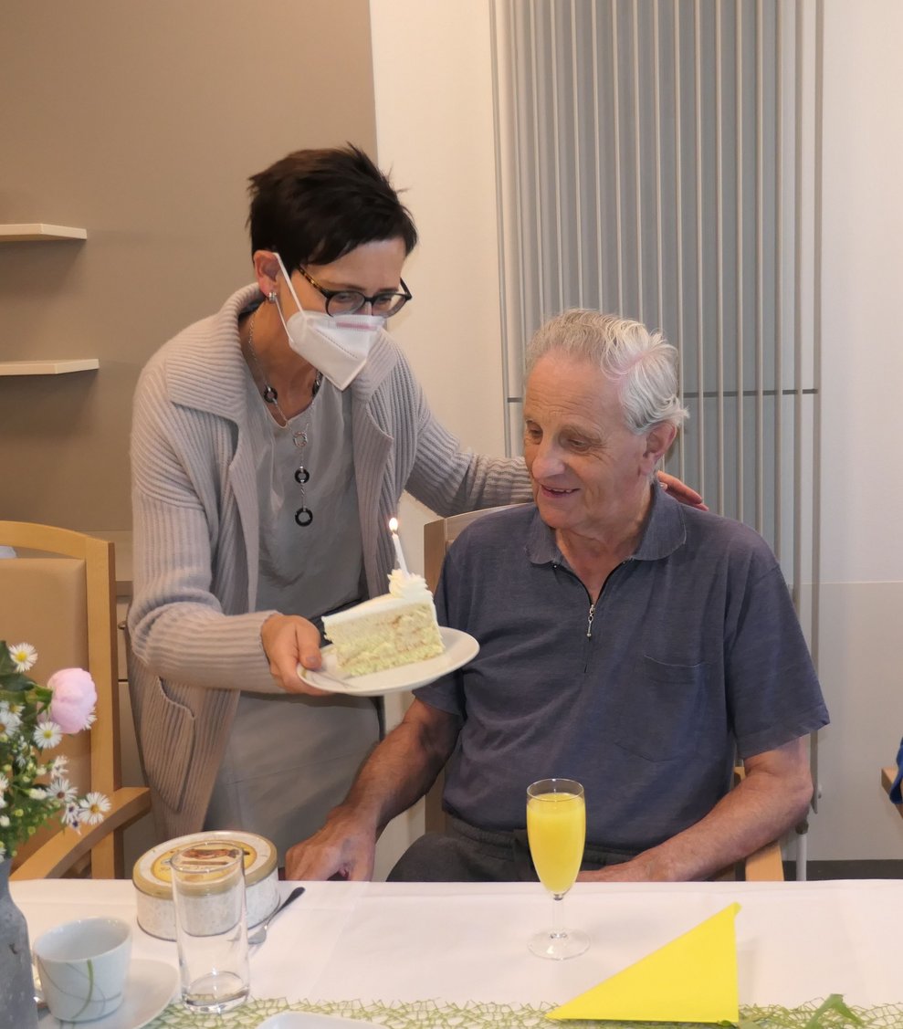 Eine Frau überreicht einem Herren ein Stück Torte.