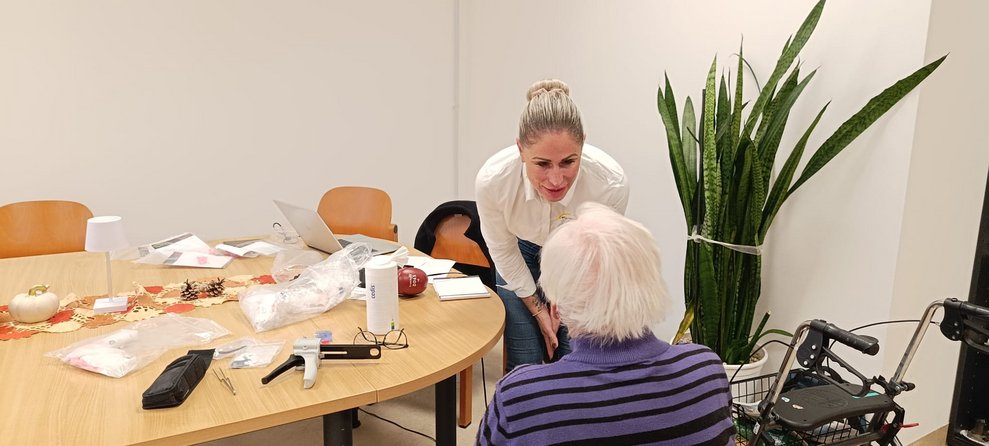 Frau beugt sich zu sitzenden Bewohner runter.