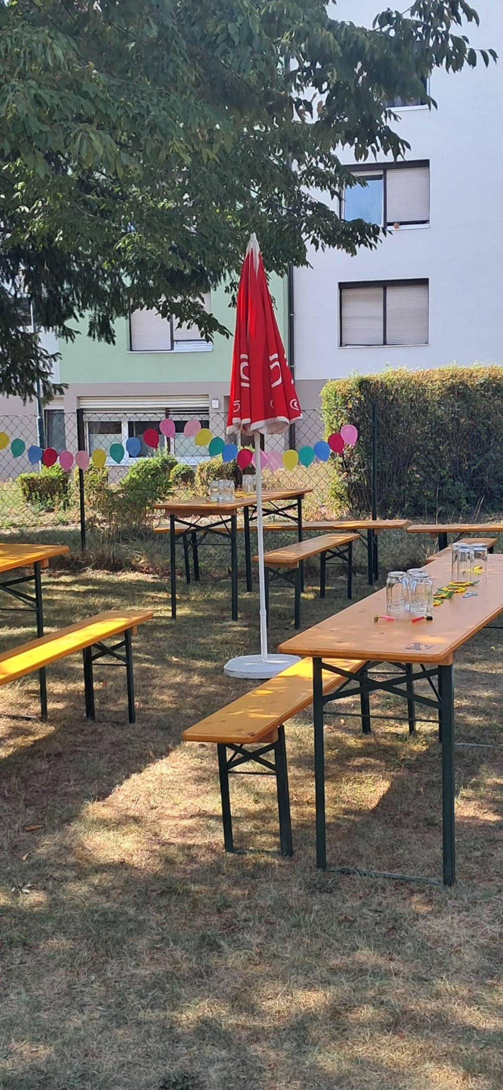 Tische, Bänke, Sonnenschirm (nicht aufgespannt) im Garten.