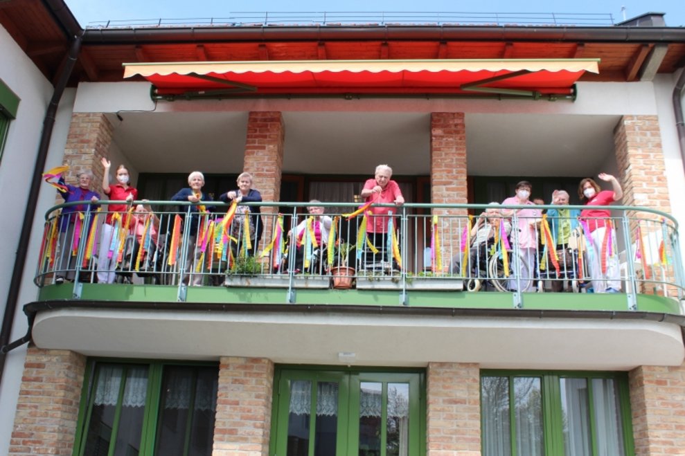 BewohnerInnen stehen am Balkon.