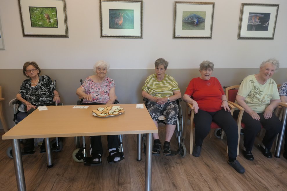 BewohnerInnen sitzen um Tisch und hören der Musik zu