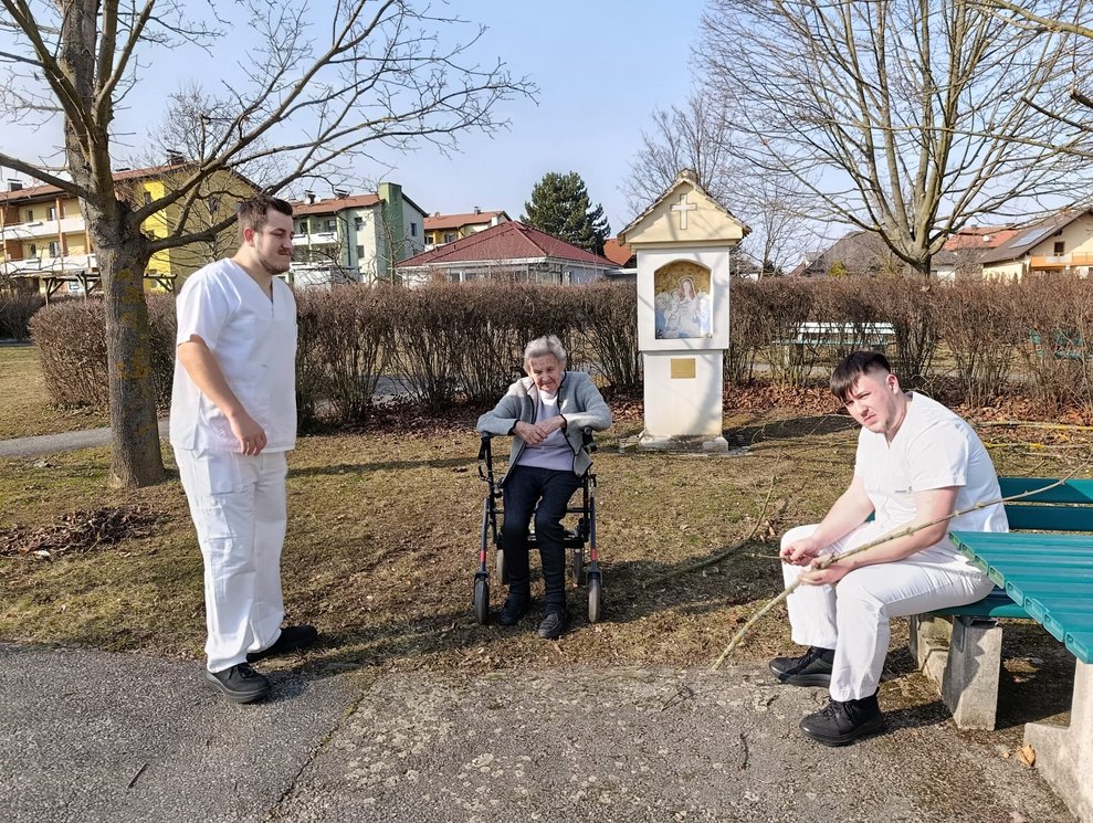 Bewohnerin und zwei Männer im Hausgarten.