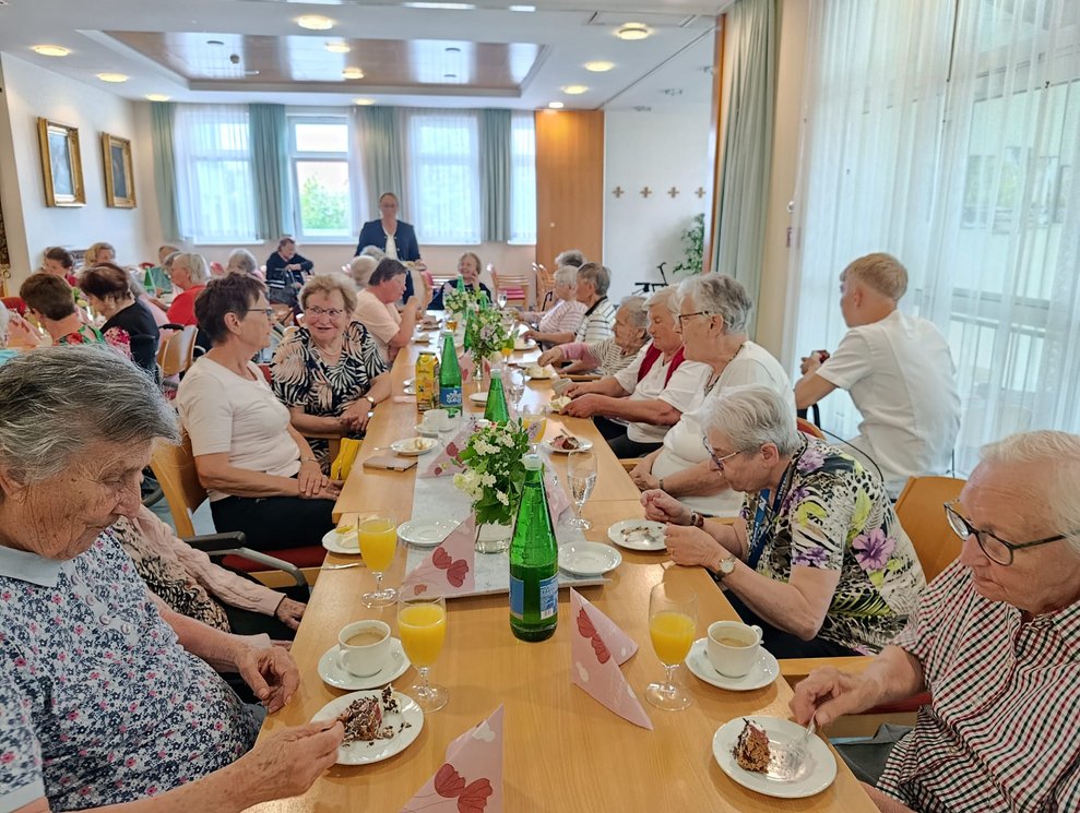 Viele beim Tisch sitzende Personen bei der Muttertagsfeier.