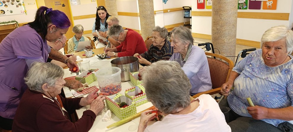 Alltagsbegleiterin schneidet Erdbeere. Bewohnerinnen beim Schneiden von Erdbeeren und Rhabarber in keine Stückchen.