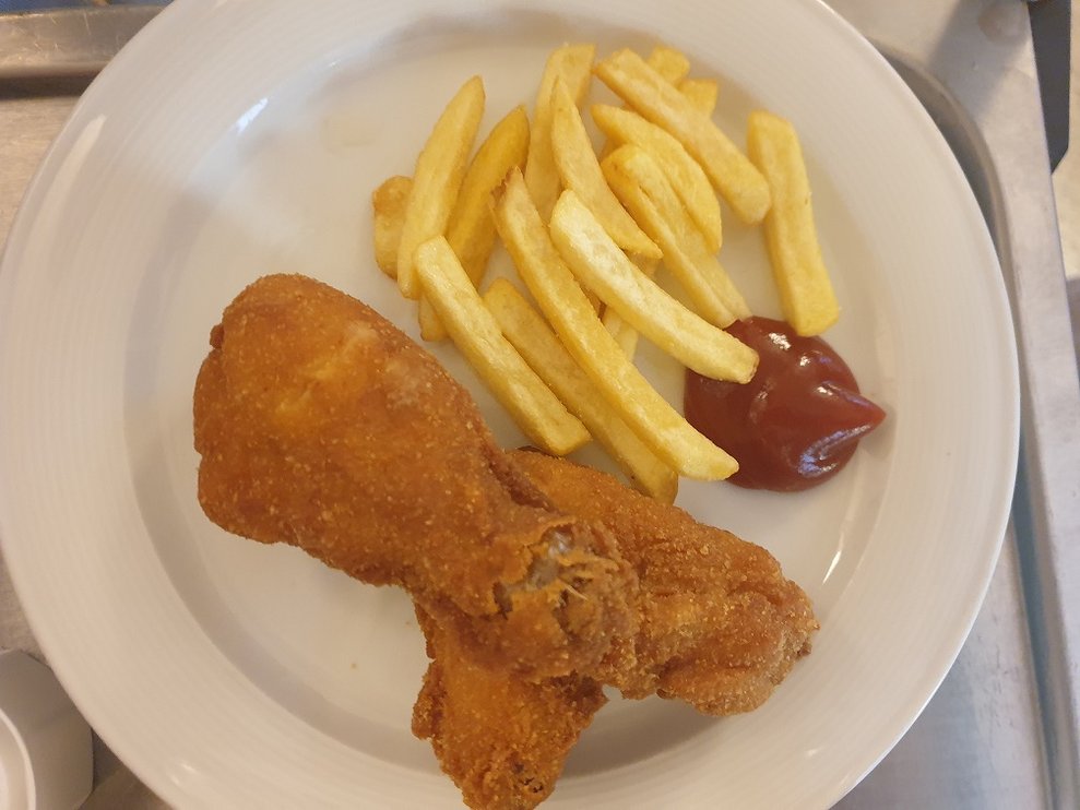 Ein Teller mit Henderl und Pommes.