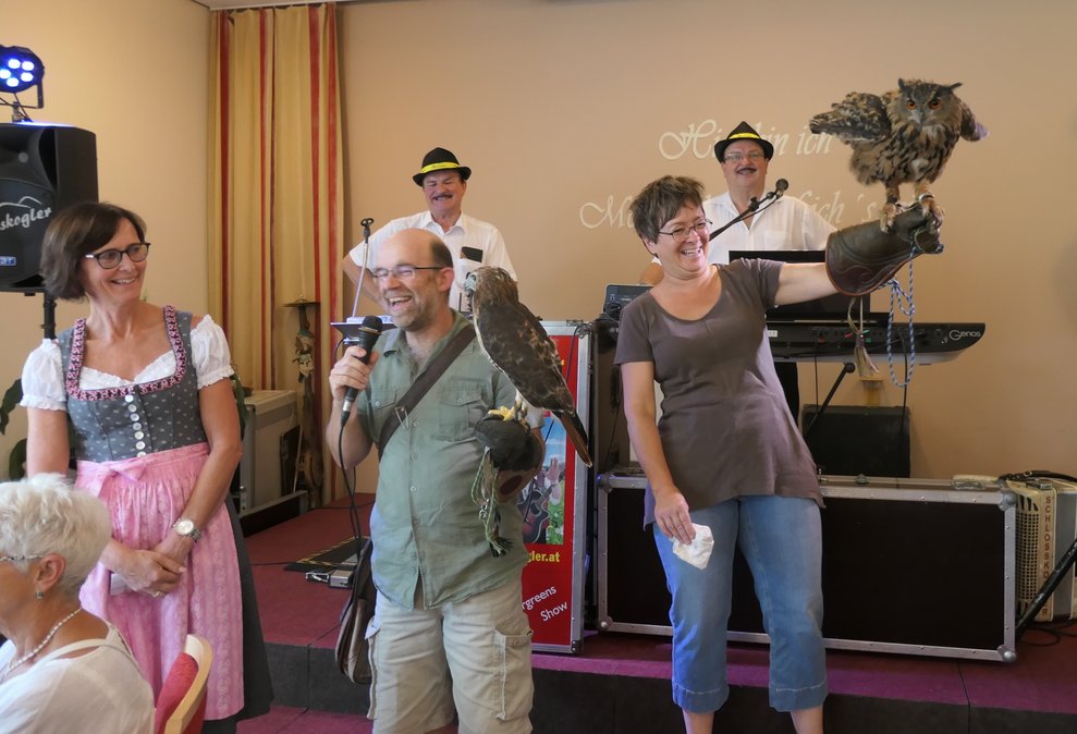 Die kaufm. Direktorin steht mit den Falknern auf der Bühne, im Hintergrund sieht man die Schlosskogler.