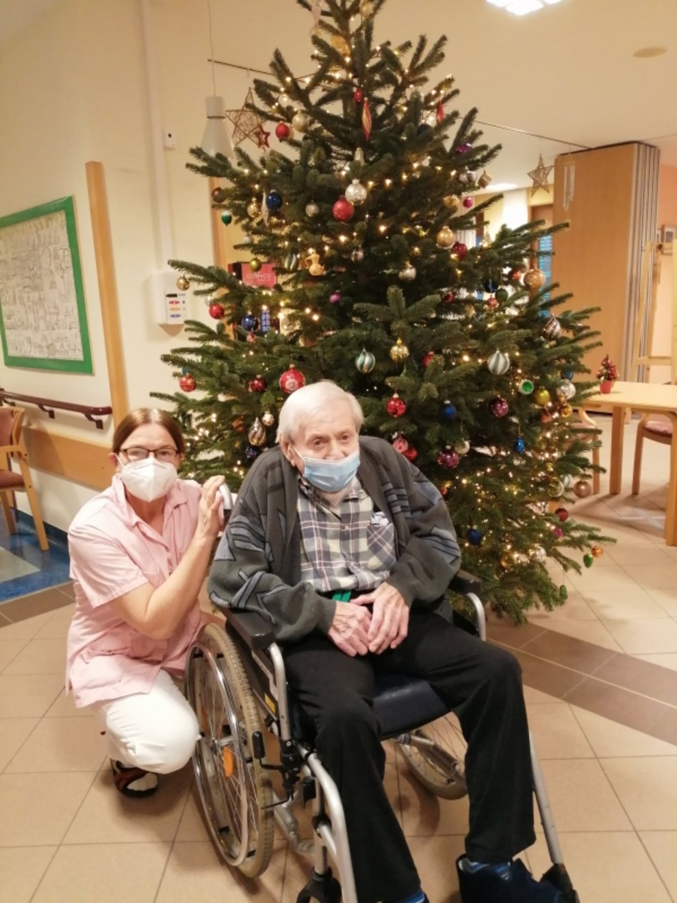 Ein Bewohner und eine Betreuerin beim Christbaum.