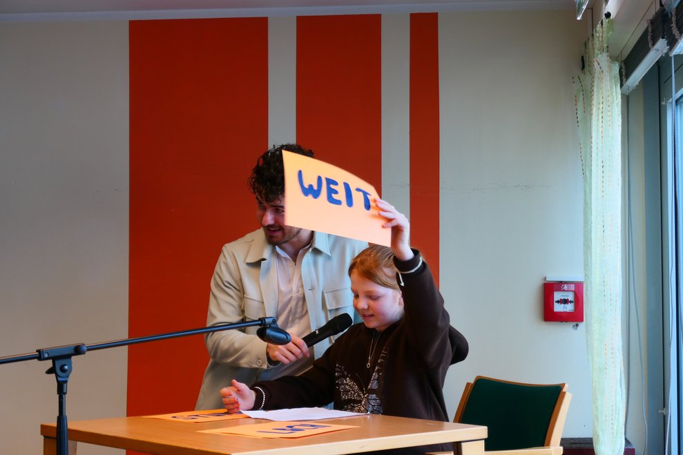 Ein Mädchen hält ein Schild in die Höhe.