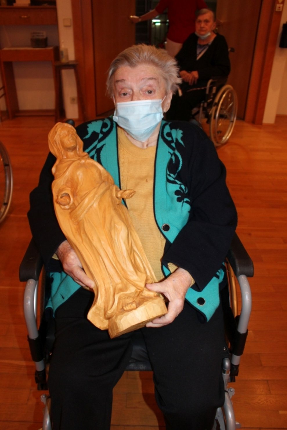 Eine Bewohnerin hält eine Mutter-Gottes-Figur.