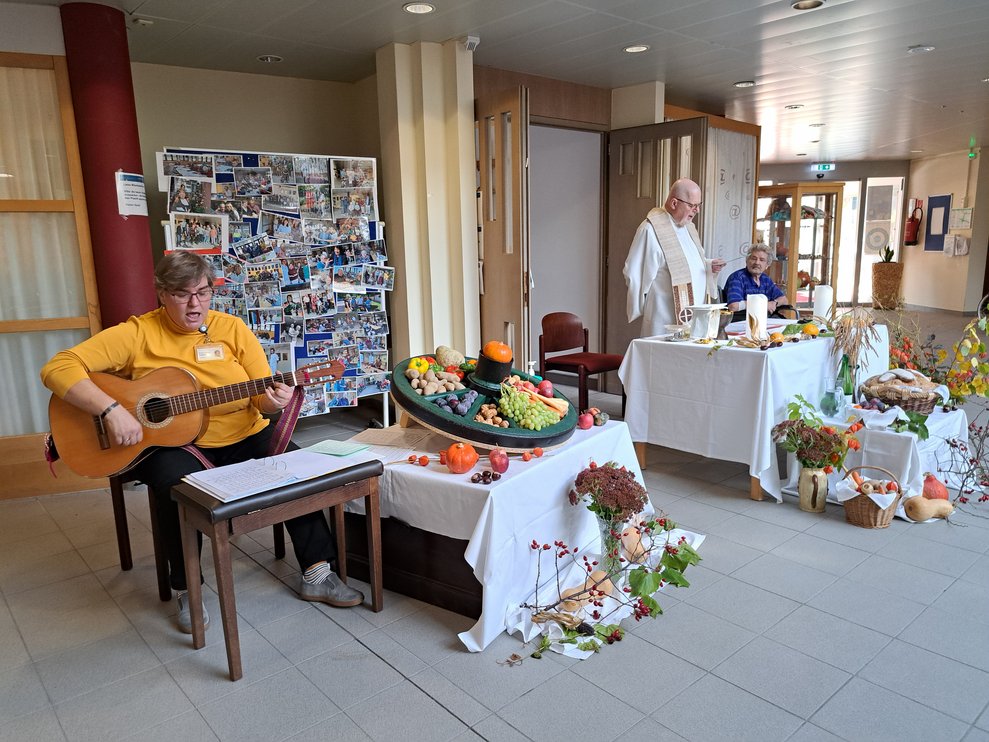 Eine Dame spielt Gitarre und singt bei der Messe. 