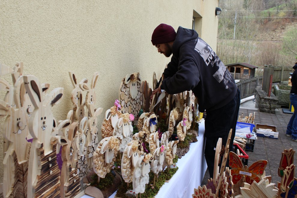 Eine Person stellt Holzhasen auf einen Tisch.