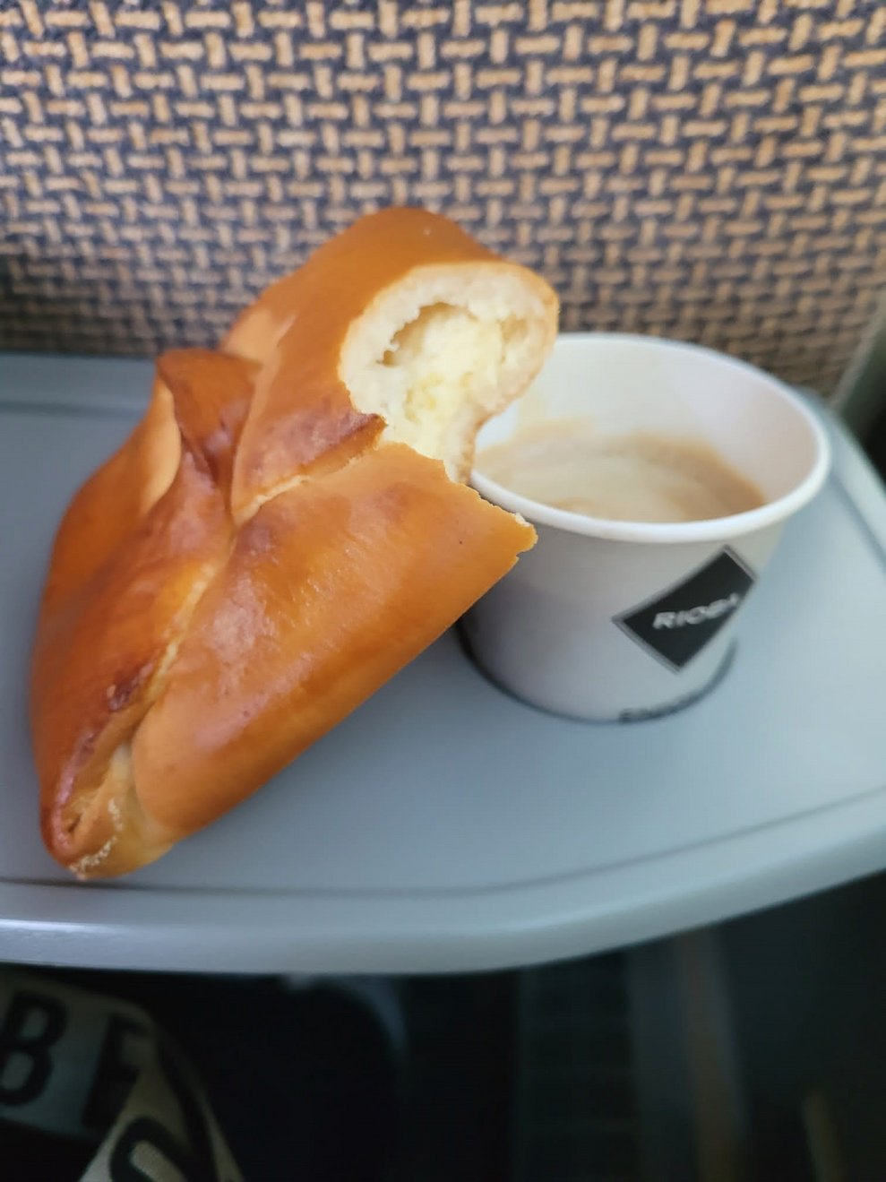 Ein Kaffee im Pappbecher und eine Topfengolatsche.