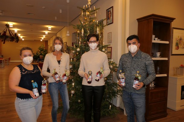Dir. Doris Bayerl übernahm stellvertretend die Geschenke. Drei Frauen und ein Mann vor dem Weihnachtsbaum.