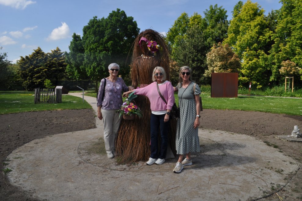 Drei Damen bei einer großen Frauen Statue aus Ästen