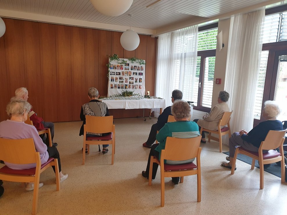 BewohnerInnen sitzen vor einer Gedenktafel.