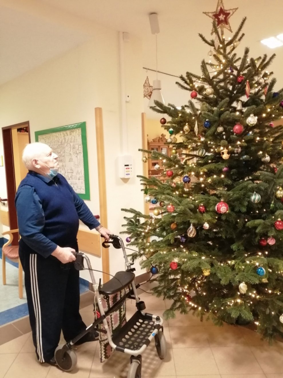 Ein Bewohner steht beim Christbaum.