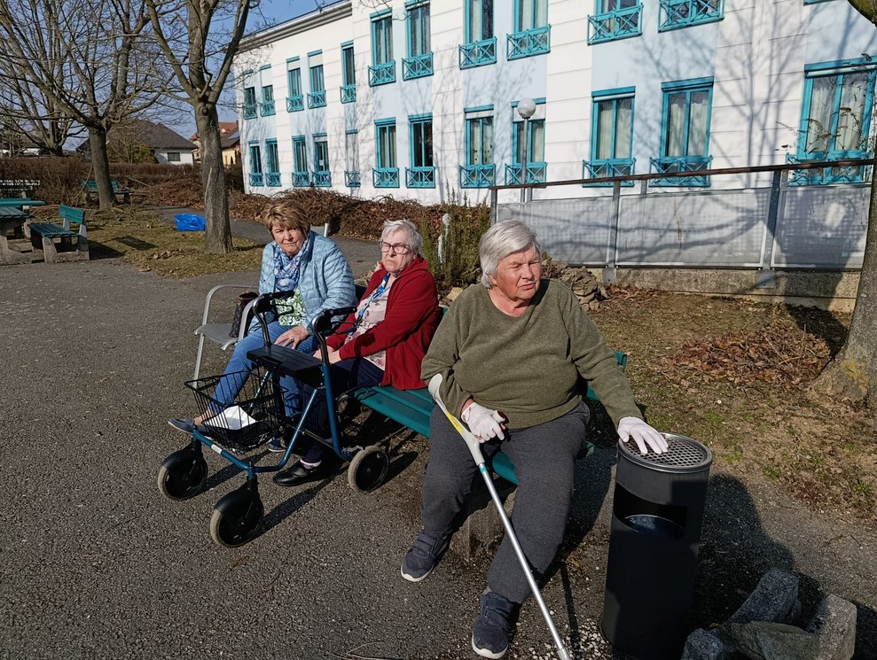 Bewohnerinnen sitzen auf Bank im Hausgarten.