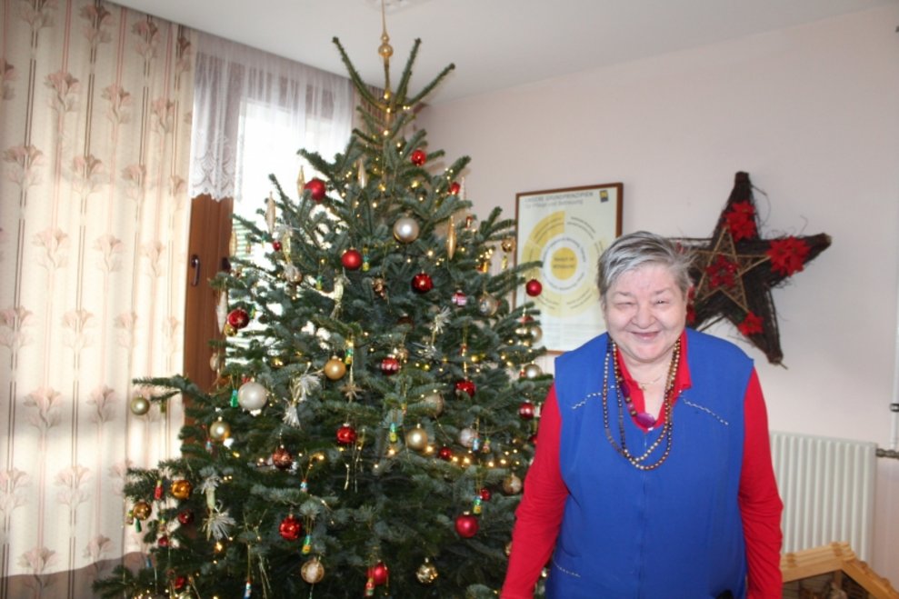 Eine Bewohnerin steht beim Christbaum.